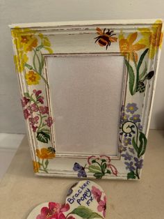 a white frame sitting on top of a counter next to a flowered heart shaped cookie