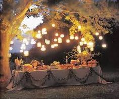 an outdoor dinner table is lit up with lanterns and paper lantern lights in the trees