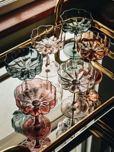 several wine glasses sitting on top of a glass shelf in front of a mirrored window