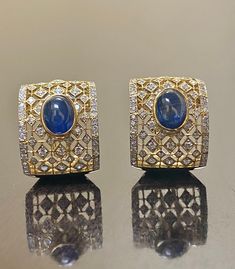 DeKara Designs Collection Metal- 18K White Gold, .750. 15.50 Grams. Stones- 2 Genuine Cabochon Oval Ceylon Blue Sapphires 5.02 Carats, 168 Round Diamonds F-G Color SI2 Clarity 2 Carats. One of a kind entirely handmade, Art Deco 18K Yellow Gold Sri Lanka Ceylon Cabochon Cut Blue Sapphire and Pave Set Diamond Art Deco Inspired One of a Kind Earrings. Each earring has an amazing oval cabochon blue sapphire that is professionally and uniquely bezel/burnish set. There are 79 round pave set diamonds o Luxury Oval Sapphire Earrings, Oval Sapphire Earrings With 17 Jewels, Formal Oval Sapphire Earrings, Luxury Oval Cabochon Gemstone Earrings, Elegant Blue Oval Cabochon Earrings, Designer Formal Gemstone Earrings, Designer Gemstone Earrings For Formal Occasions, Luxury Oval Earrings For Formal Occasions, Luxury Diamond Cabochon Earrings