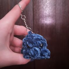 a hand holding a small blue flower keychain