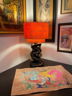 a lamp on a table next to an old piece of paper with a snake painted on it