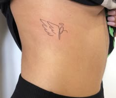 a small tattoo on the back of a woman's lower body, with an angel wing