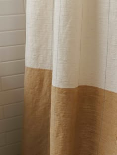 a close up of a shower curtain with white and brown stripes on it in a bathroom