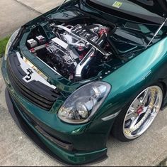 a green sports car with an engine in it's hood parked on the street