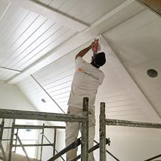 a man is painting the ceiling in an unfinished room with scaffolding on it