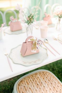 a white table topped with pink bags and silverware on top of a grass covered field