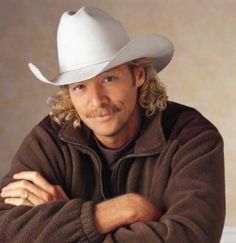 a man wearing a white cowboy hat with his arms crossed