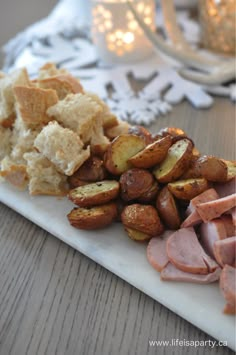 ham, potatoes and bread on a white plate with christmas lights in the back ground