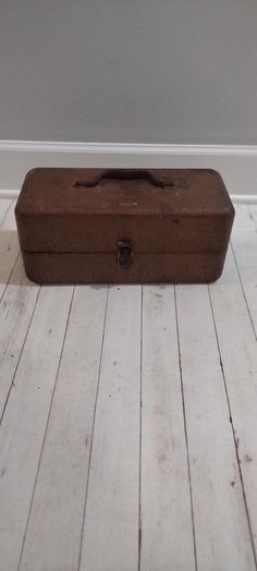 an old wooden box sitting on the floor in front of a white wall and wood floors