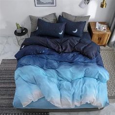 a bed with blue and white comforters in a room next to a painting on the wall