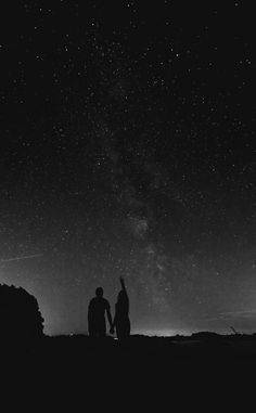 two people standing on top of a hill under the stars