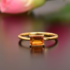 an orange ring sitting on top of a table next to pink flowers and a rose