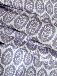 purple and white fabric with an ornate design on it's side, folded in half