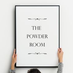 a person holding up a black and white poster with the words the powder room on it