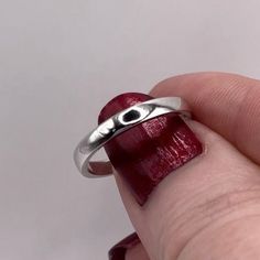 a hand holding a silver ring with an evil eye on it