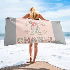 a woman standing on the beach holding a chanel towel in front of her back