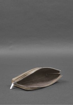 an empty silver purse on a gray background with the zipper open to show it's contents