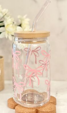 a glass jar with pink bows on it and two cork coasters next to it