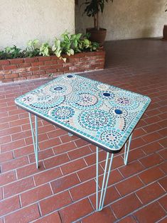 a table sitting on top of a red brick floor next to a planter filled with potted plants