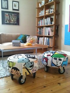 two colorful stools sitting on top of a hard wood floor in front of a bookshelf