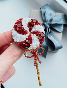 a hand holding a red and white brooch with a gold key attached to it