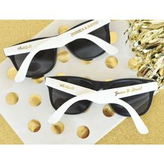 two black and white sunglasses with gold confetti on the table next to them