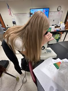 a woman is looking through a microscope at something on the table in front of her