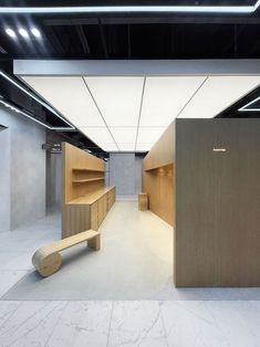 an empty room with benches and shelves in the center is lit by recessed lights