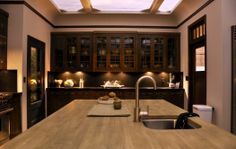 a large kitchen with wooden cabinets and counter tops is lit by recessed lights above the sink