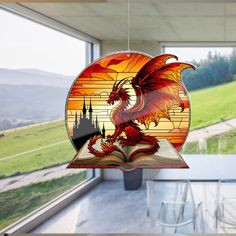 a stained glass window with a red dragon on it's side and an open book in the foreground