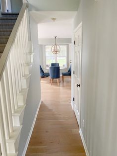 a hallway leading to a dining room and living room with blue chairs on either side