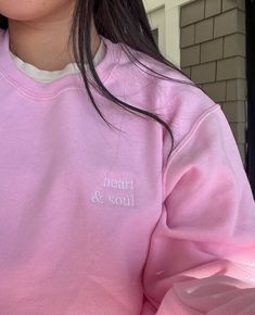 a girl wearing a pink sweatshirt with the words heart and soul embroidered on her chest