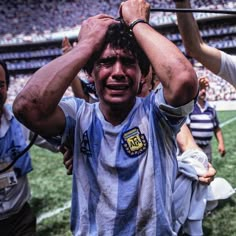 a soccer player is holding his head in the air while other players stand behind him