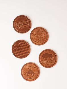 four brown leather coasters with different designs on the front and back, including an american flag