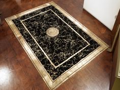 a black and gold area rug on the floor in a room with hard wood floors