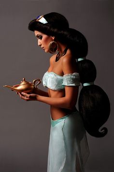 a woman dressed as disney princess holding a teapot and looking down at her stomach