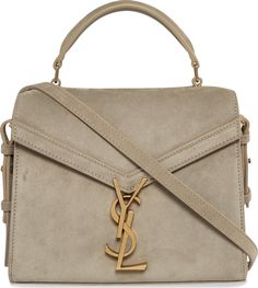 The YSL Mini Cassandra Top Handle Bag epitomizes sophistication and luxury with its exquisite craftsmanship and timeless design. Crafted in Italy from sumptuous suede, complemented by leather lining and antique gold-tone hardware, this bag exudes opulence at every turn. Its compact yet functional silhouette features a fold-over flap top closure adorned with a pivoting YSL emblem, adding a touch of iconic elegance. Inside, two spacious compartments and an interior flat pocket offer ample storage, Ysl Mini Cassandra, Fashion Today, In Depth, Handle Bag, Womens Tote Bags, Antique Gold, Top Handle, 6 Inches, Bags Women