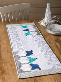 a wooden table with a quilted placemat on it and a silver plate next to it