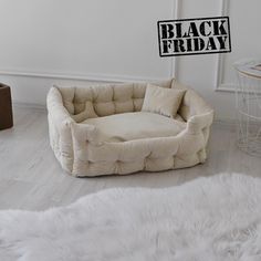 a white dog bed sitting on top of a hard wood floor next to a table