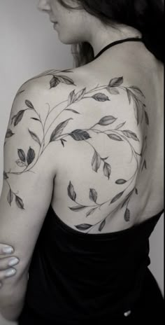 a woman wearing a black dress with leaves on her chest and shoulder tattoo design in grey ink