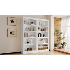 a white bookcase with many books on it next to a window in a living room