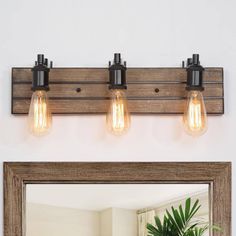 a bathroom vanity light with three bulbs on the wall and a mirror in front of it