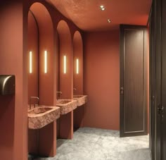 a row of sinks sitting next to each other in a room with red walls and columns