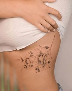 a woman's stomach with a flower tattoo on her side and the bottom part of her belly