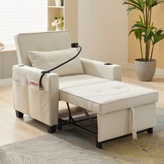 a living room with a white chair and footstool in front of a potted plant