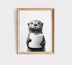 a black and white photo of an otter holding a roll of toilet paper in its paws