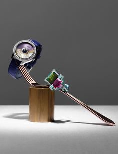 a toothbrush and watch sitting on top of a wooden stand in front of a gray background