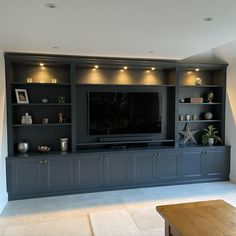 a large entertainment center with built in shelves and lights on the top, along with a flat screen tv