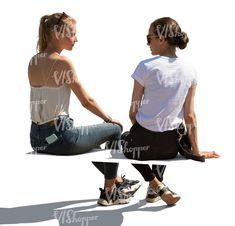 two women sitting on the ground with their backs to each other